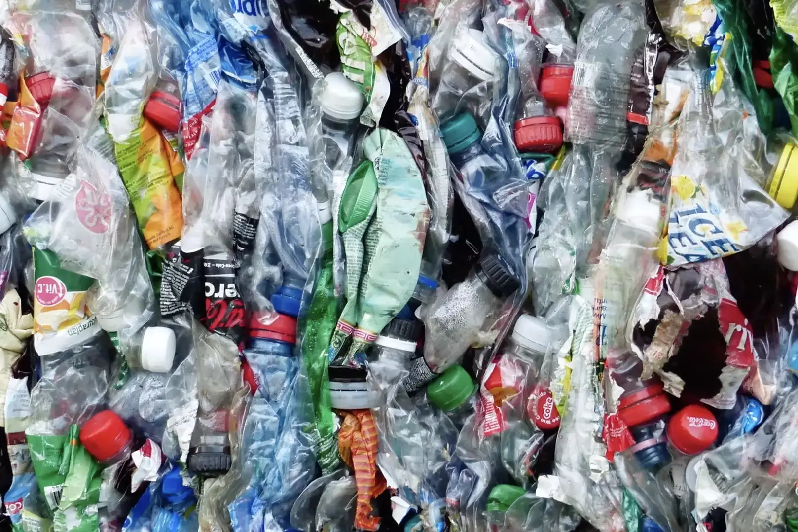 Zusammengepresste Kunststoffabfälle mit zahlreichen Plastikflaschen und Verpackungen in einer Ballenpresse für das Recycling.