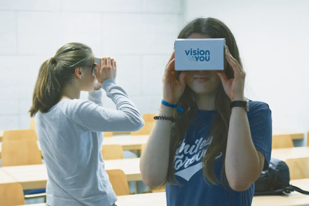 Zwei Schülerinnen testen VR-Brillen von visionYOU in einem Klassenraum.