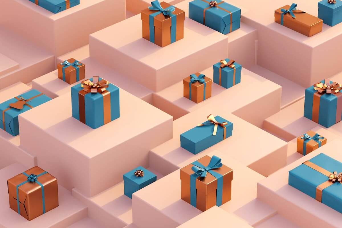 Blau und orange verpackte Geschenke auf abgestuften rosafarbenen Flächen.
