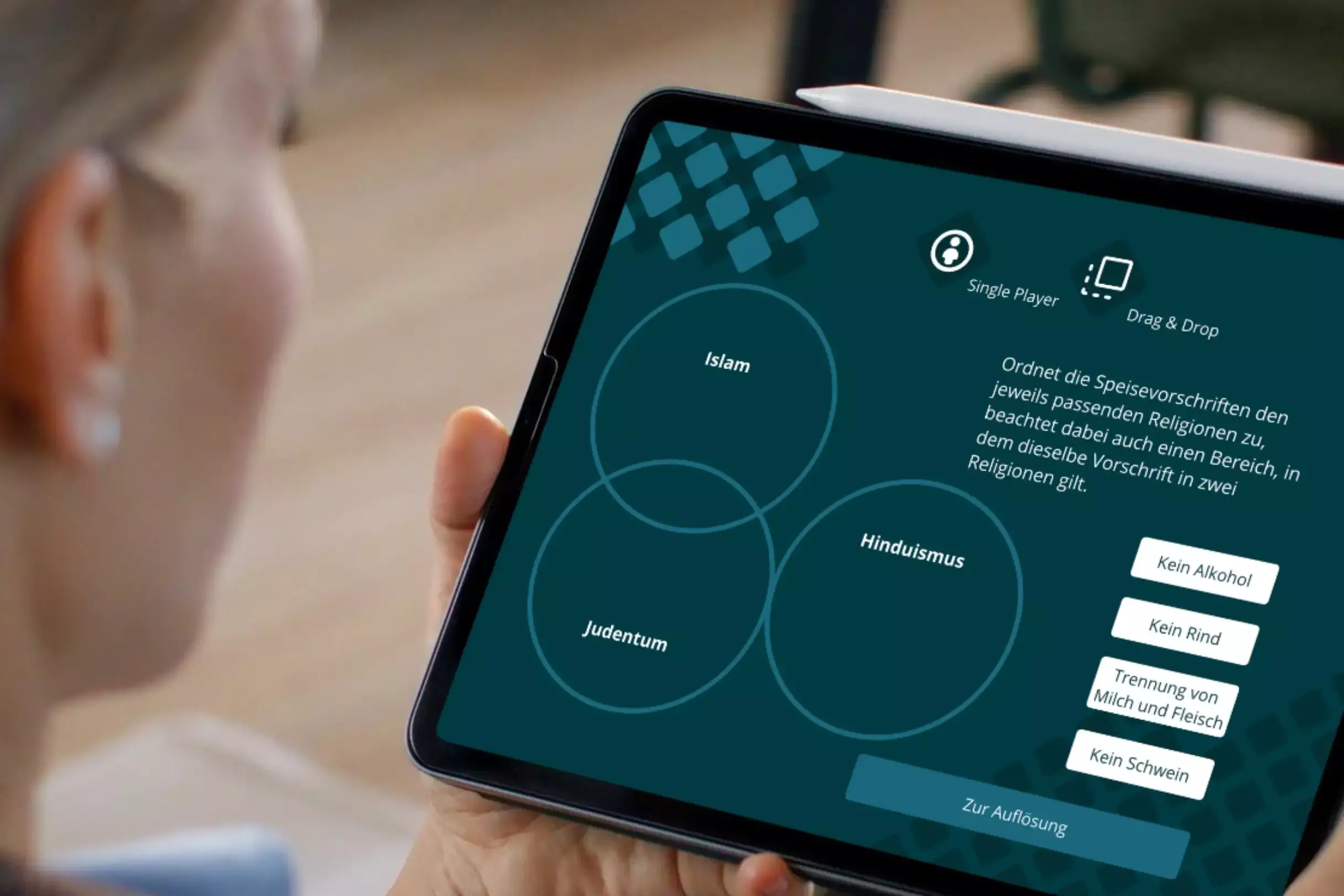 Person bearbeitet auf einem Tablet eine Drag-and-drop-Aufgabe aus dem Spiel
