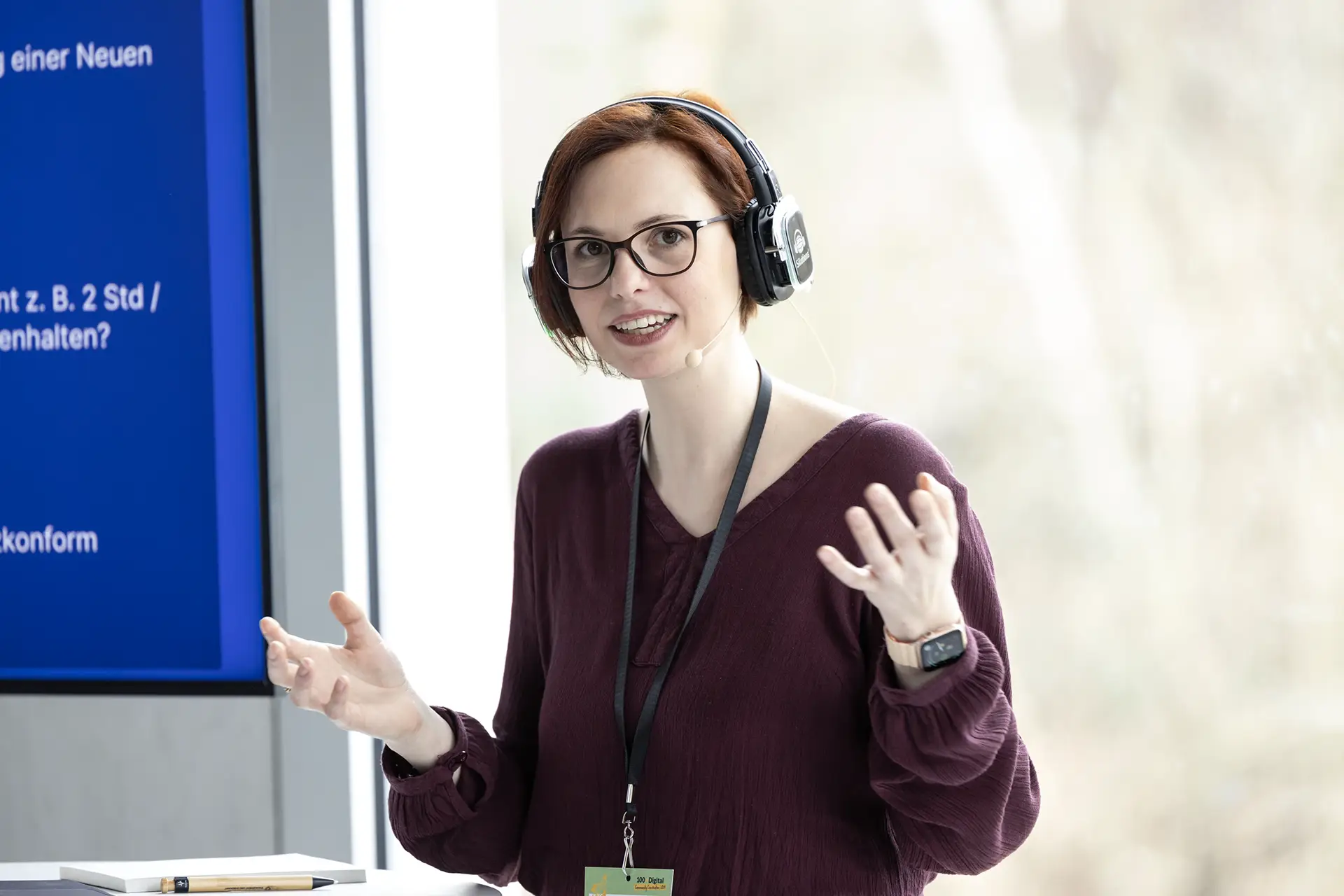 Referentin mit Headset gestikuliert während eines Vortrags bei einer 100xDigital-Veranstaltung.