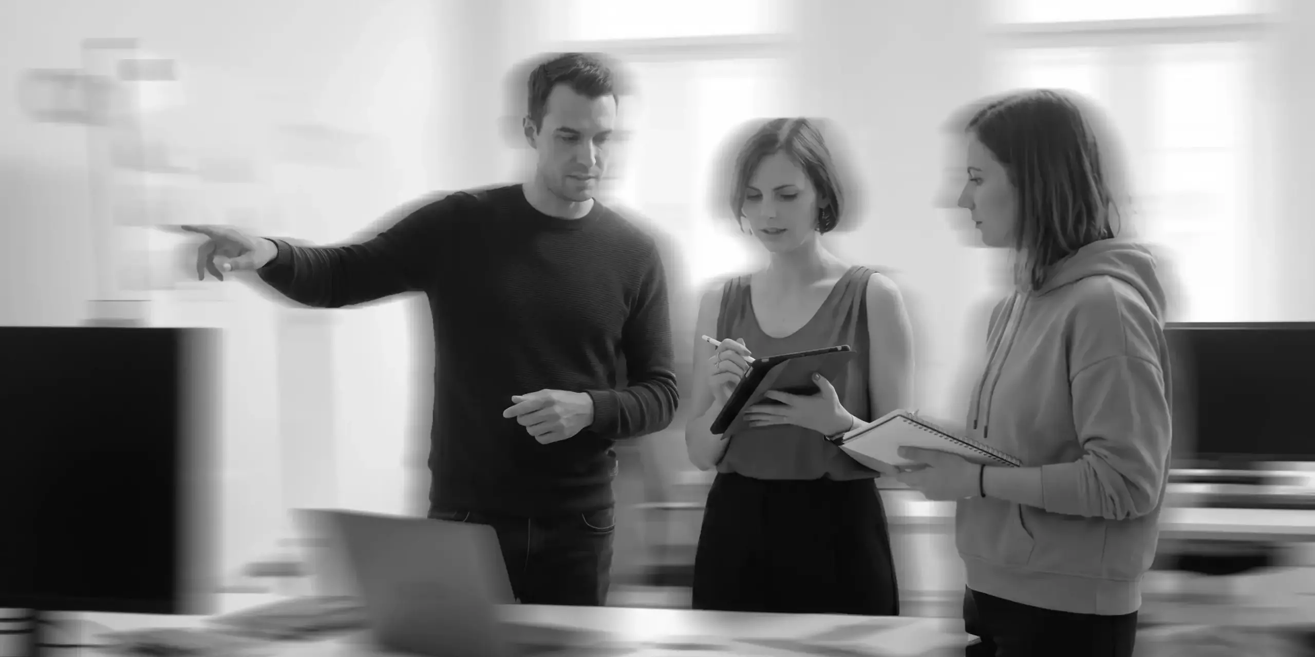 Drei Personen entwickeln gemeinsam Ideen und arbeiten mit Laptop, Tablet und Notizblock.