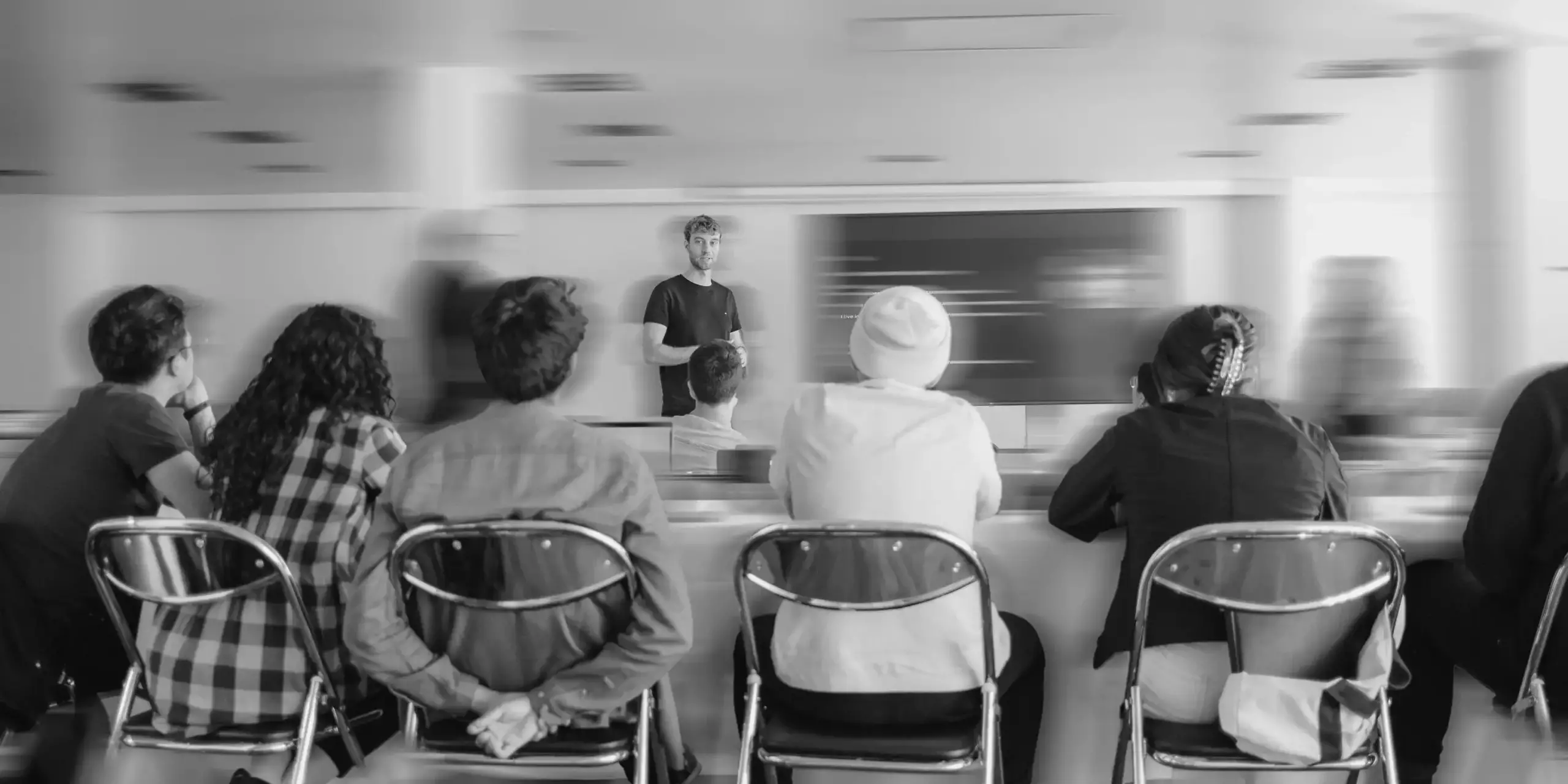 Referent spricht vor einer Gruppe sitzender Teilnehmender in einem Workshop.
